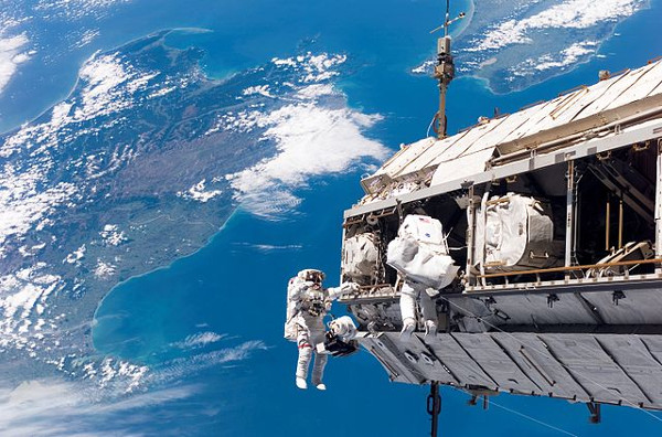 Astronauts on space walk with ocean in background