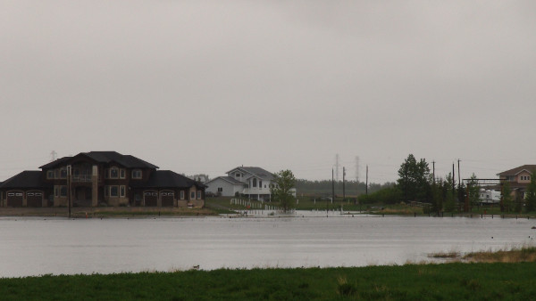 Image showing properties in Conrich where high water level of pond is nearing the house.